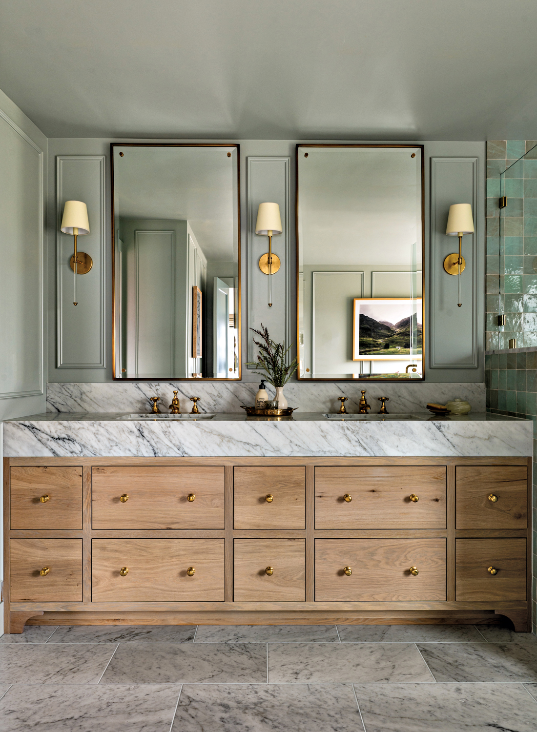 Bathroom with wood vanity topped by grey-veined stone beneath two rectangular mirrors by Jessica Nelson