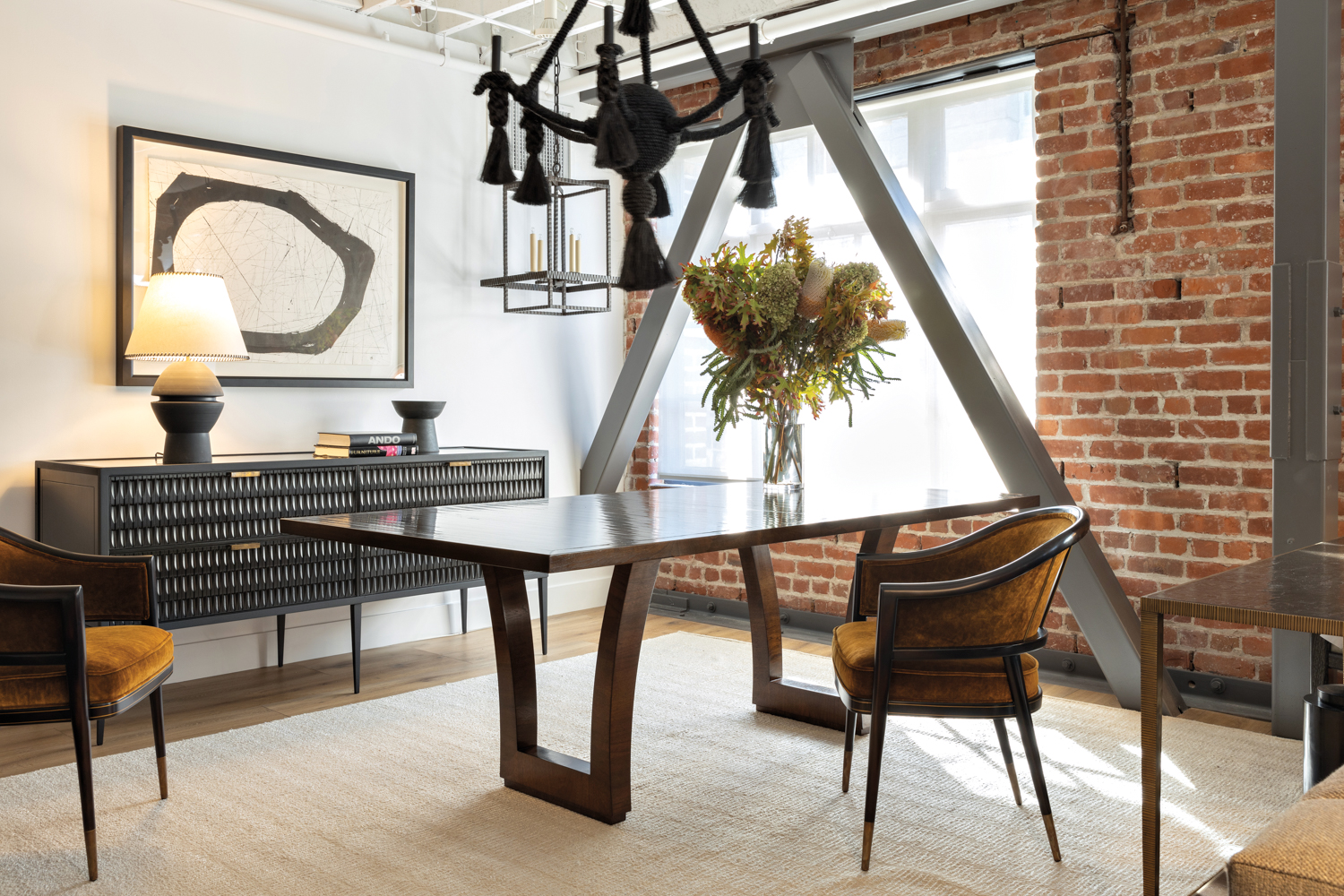 Hewn furniture showroom with black chandelier over wood dining table and chairs 