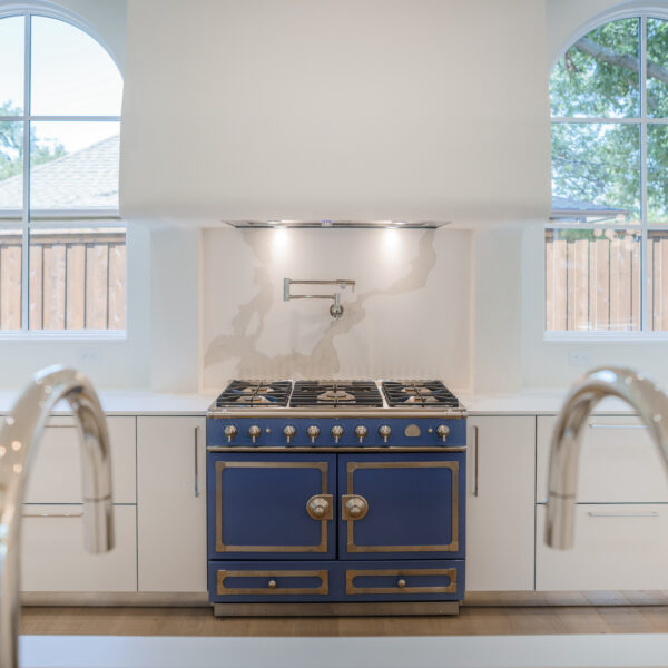 A white kitchen with a blue and gold detailed stove.