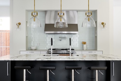 Marble kitchen island with sleek black details and pendant lighting.