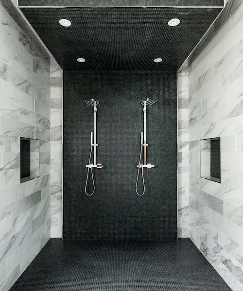 Monochrome spacious shower featuring black and white tiling.
