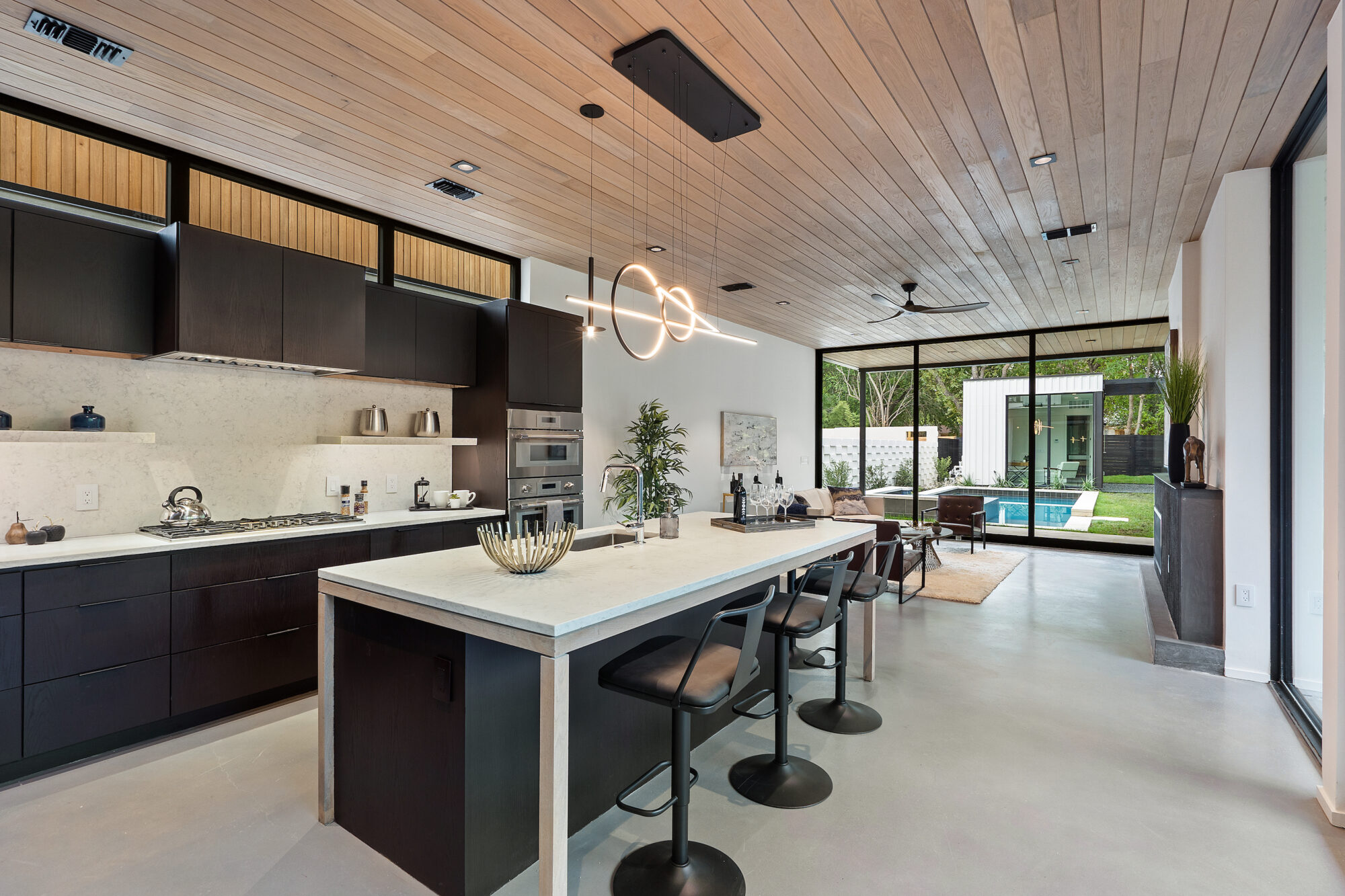 A contemporary kitchen featuring a wooden ceiling and sleek black appliances.
