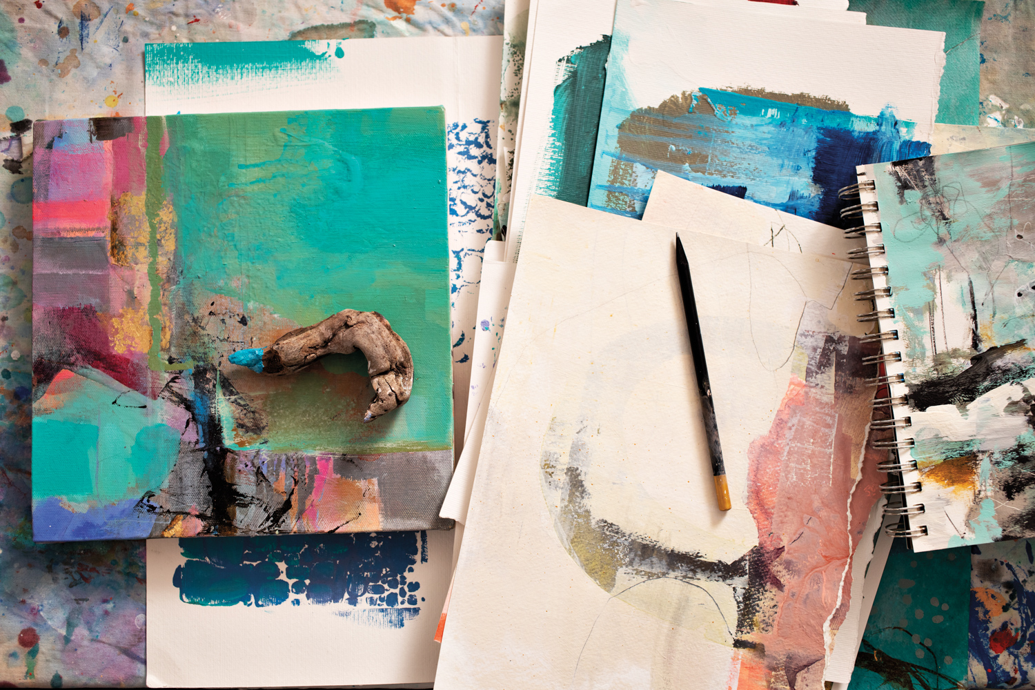A collection of sketchbooks covered in abstract paintings.