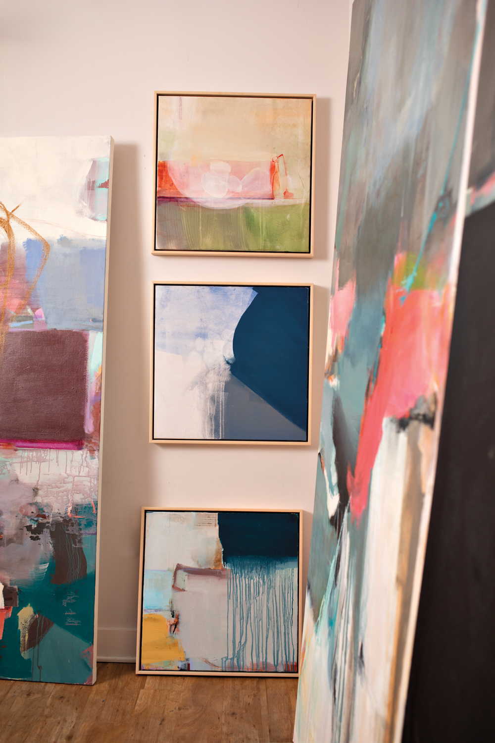 Abstract paintings hanging vertically down a wall.