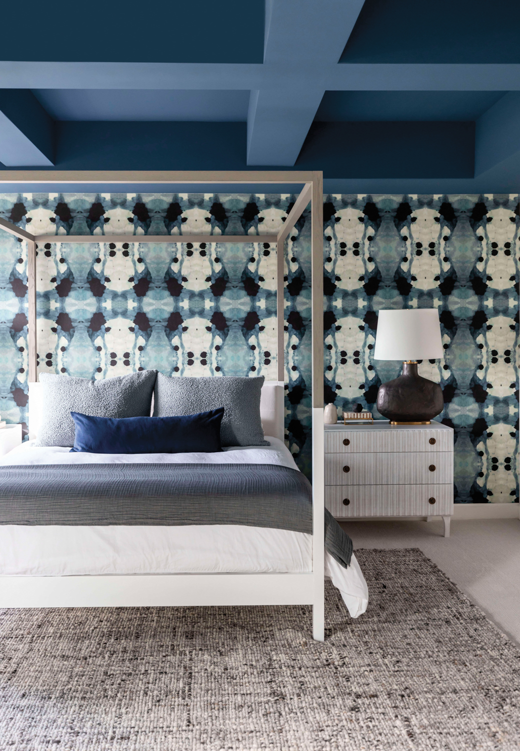 Bedroom with graphic blue-and-white wallpaper and coffered ceiling coated in blue paint
