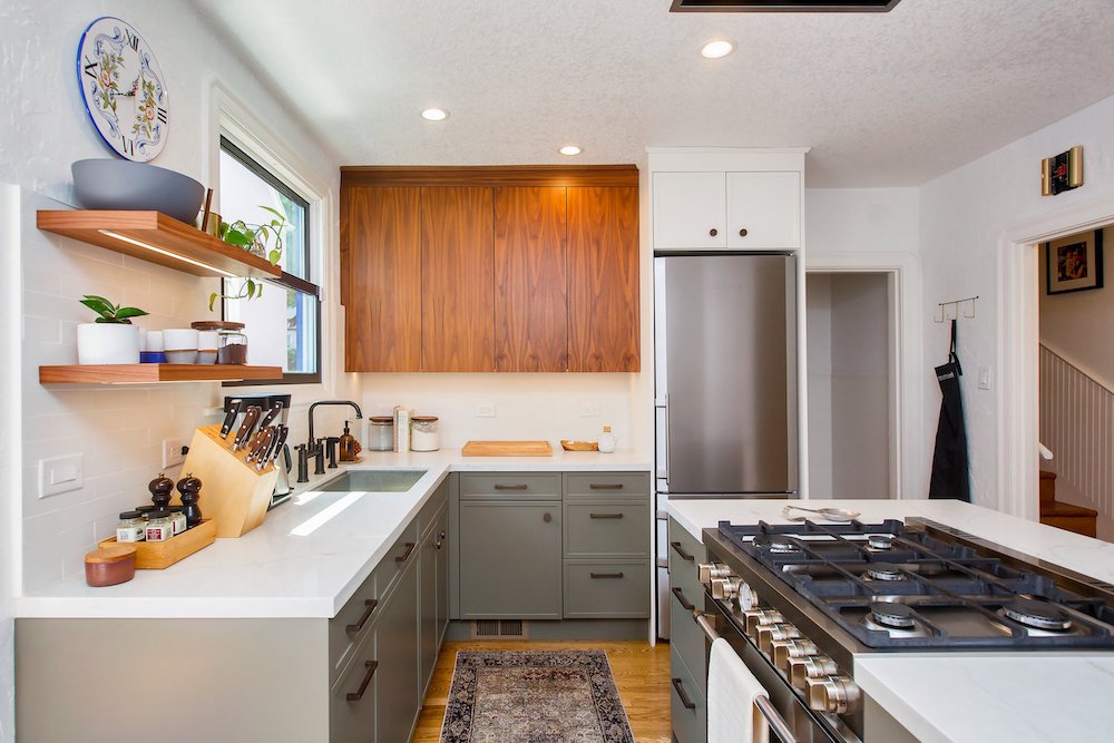 a kitchen featuring a modern design with grey lower cabinets contrasting against wood upper cabinets. The wood floor adds a vibrant touch to the space. Stainless steel appliances seamlessly blend in, contributing to the contemporary aesthetic of the kitchen.