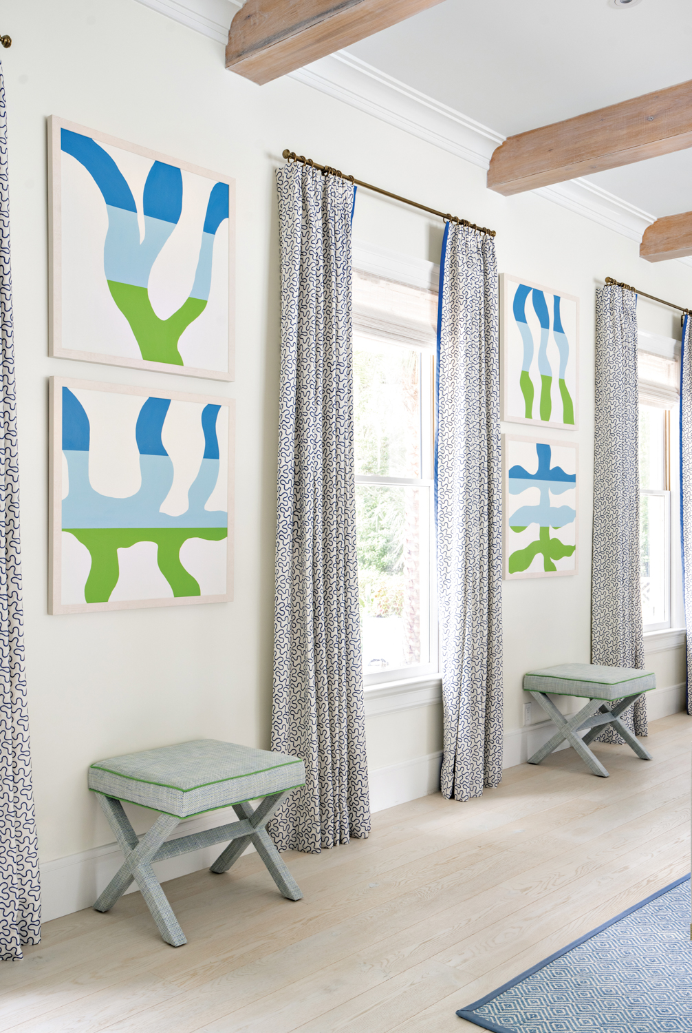 Hallway with blue-and-green abstract artworks flanking a window with patterned curtains