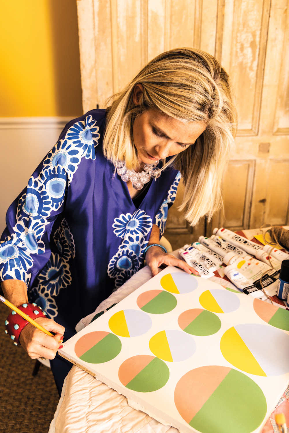Artist Katie Powell Brickman signing one of her paintings featuring multicolored circles