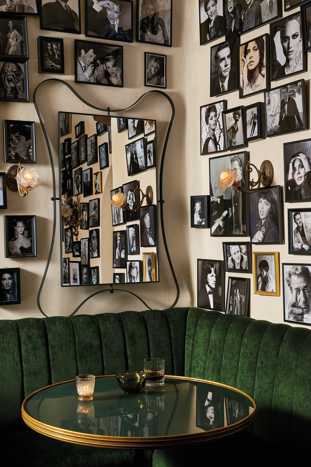 a wall filled with portraits of actors above a dark green corner booth