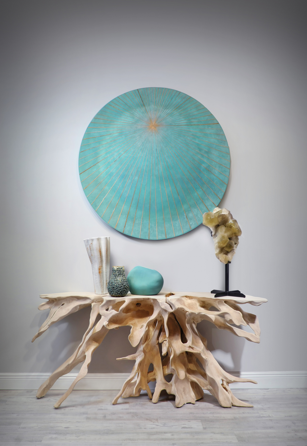 live edge wood table with root sculpted base with a round aqua-colored artwork hanging above. 