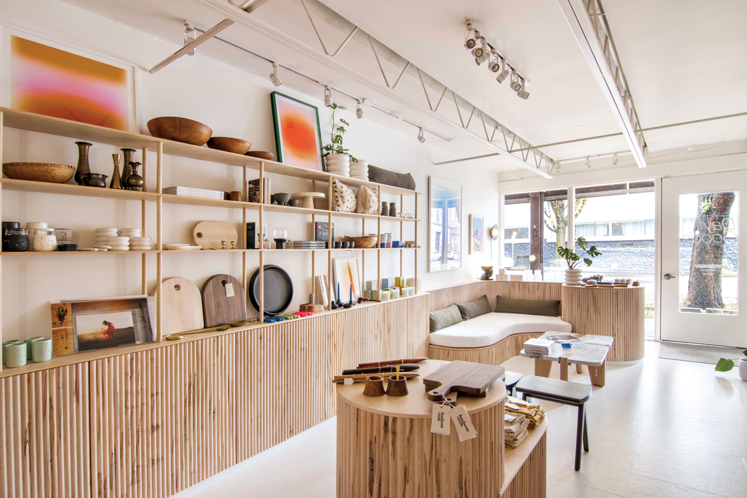 Store with fluted wood cabinets and tables showcasing home goods like cutting boards and dishware.