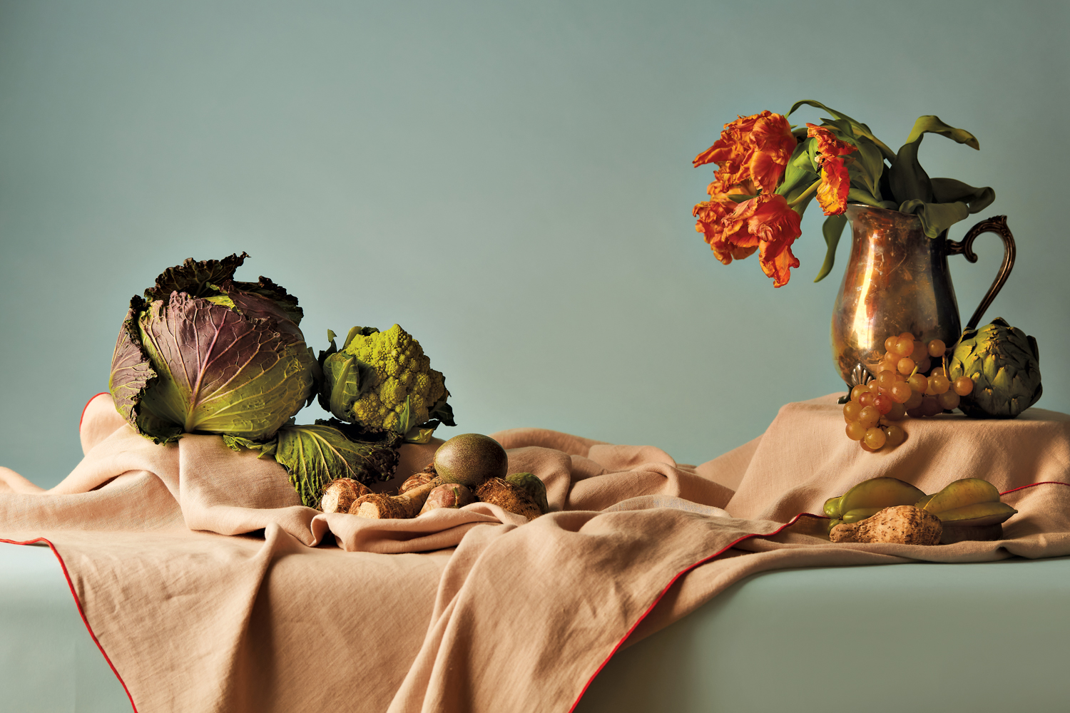 Ocher-colored tablecloth topped with orange flowers and various green vegetables.