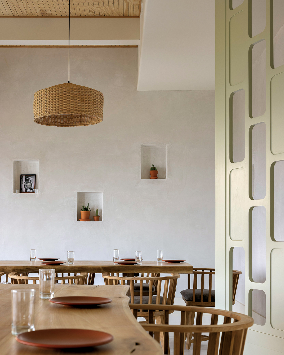 restaurant with cream-colored plaster walls, wood tables and chairs, and a rattan chandelier