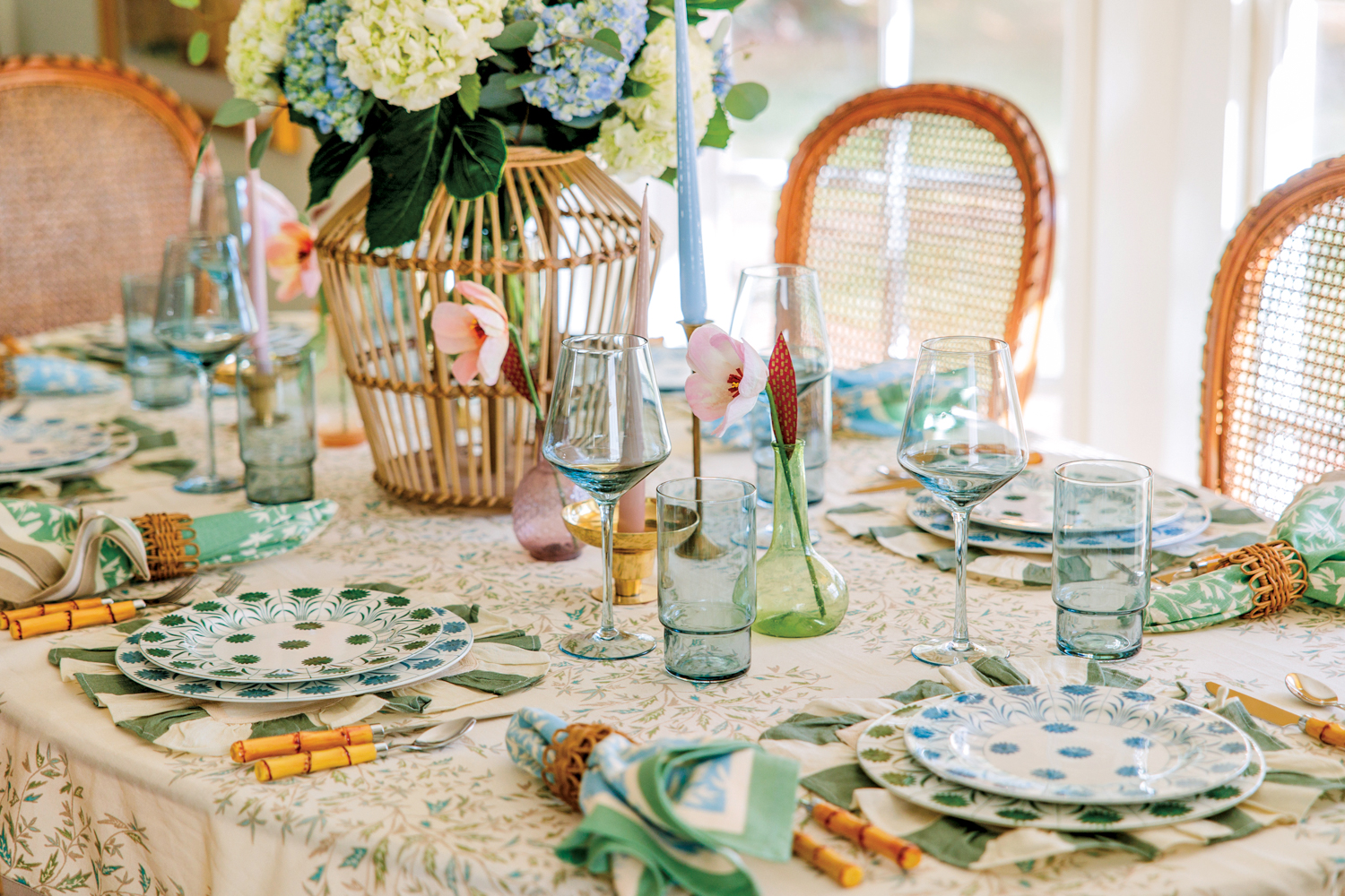 Styled tabletop with green and blue place settings with bamboo-handled utensils. 