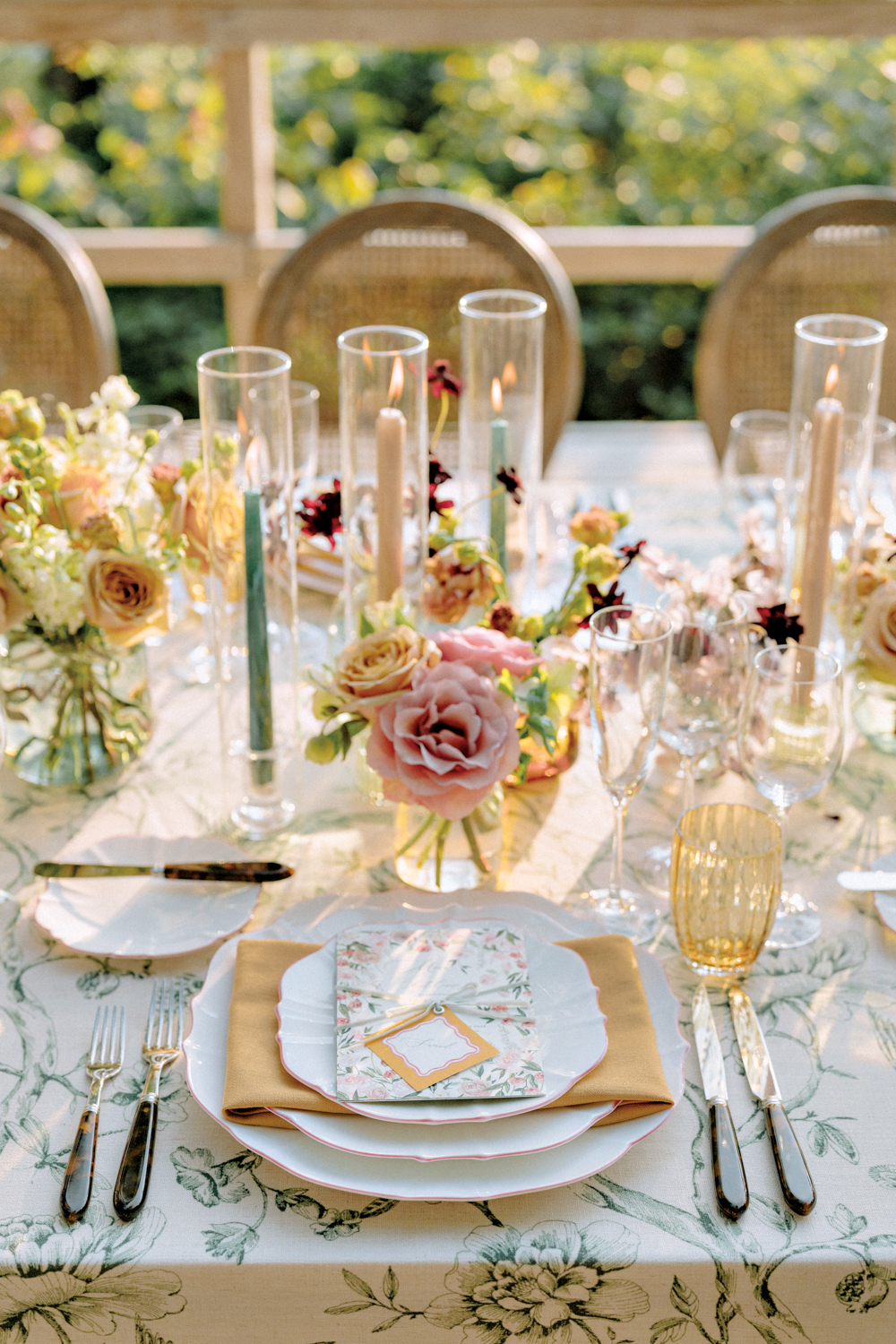 Styled tabletop with cream and pink flowers and long steam candles. 