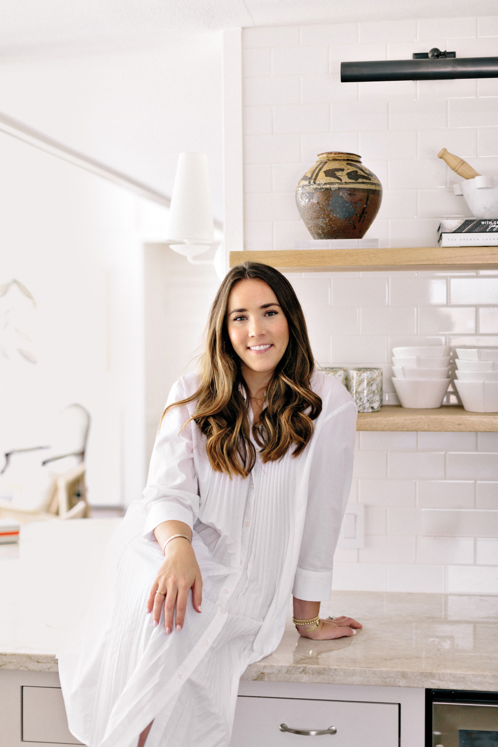 Amanda Lodge sitting on a counter in a white kitchen