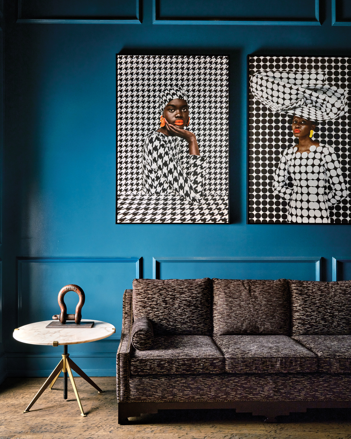Two portraiture artworks above a sofa and against blue painted wall