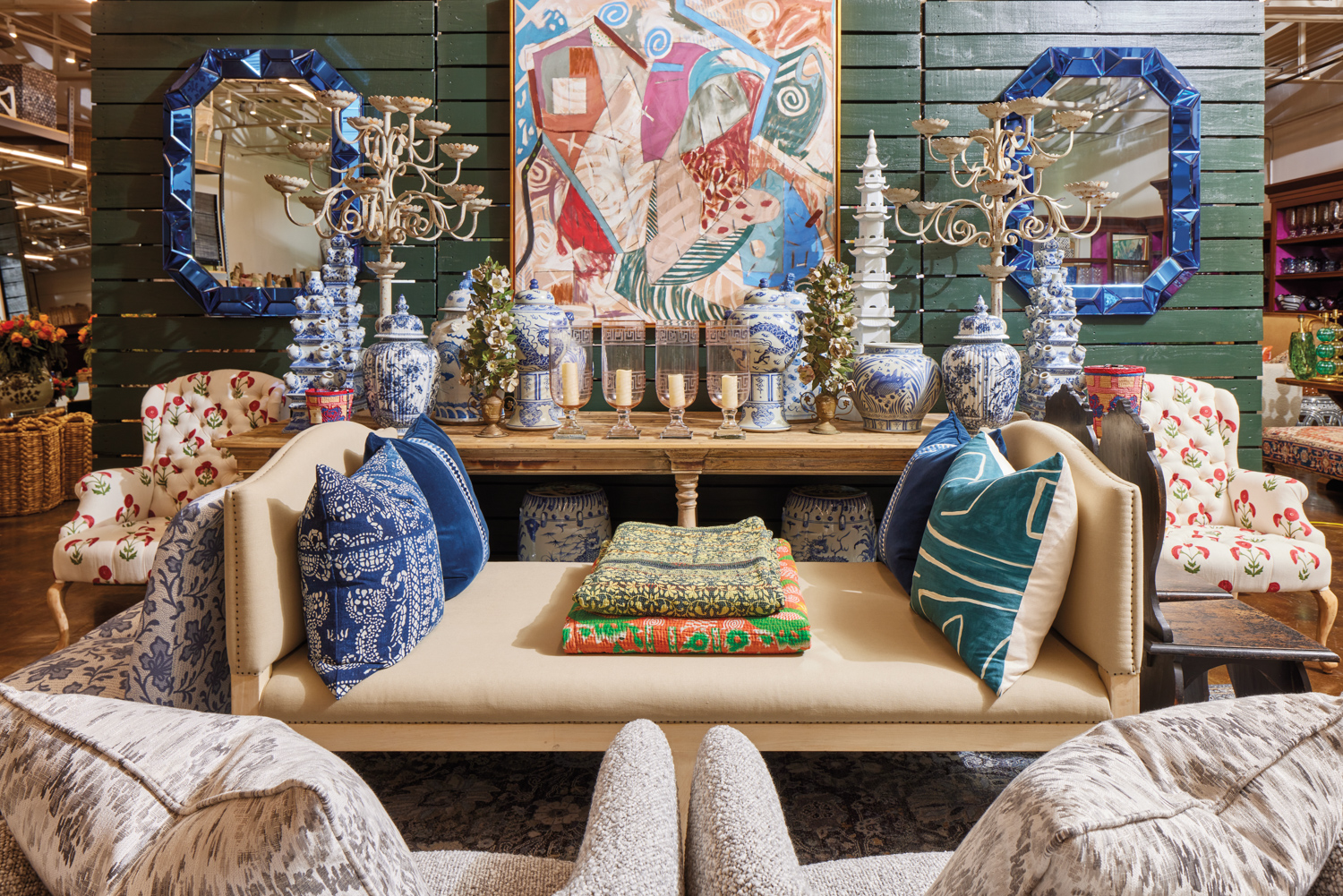 Curated showroom vignette of seating, pillows, chinoiserie vessels and mirrors
