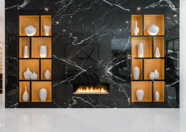 A fireplace with shelves and recessed lighting illuminating vases.