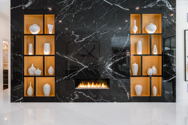 A fireplace with shelves and recessed lighting illuminating vases.