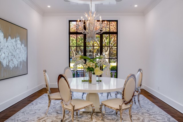 A white table with chairs and a chandelier.