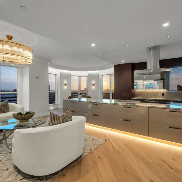 A living room with a kitchen and a large island with lighting.