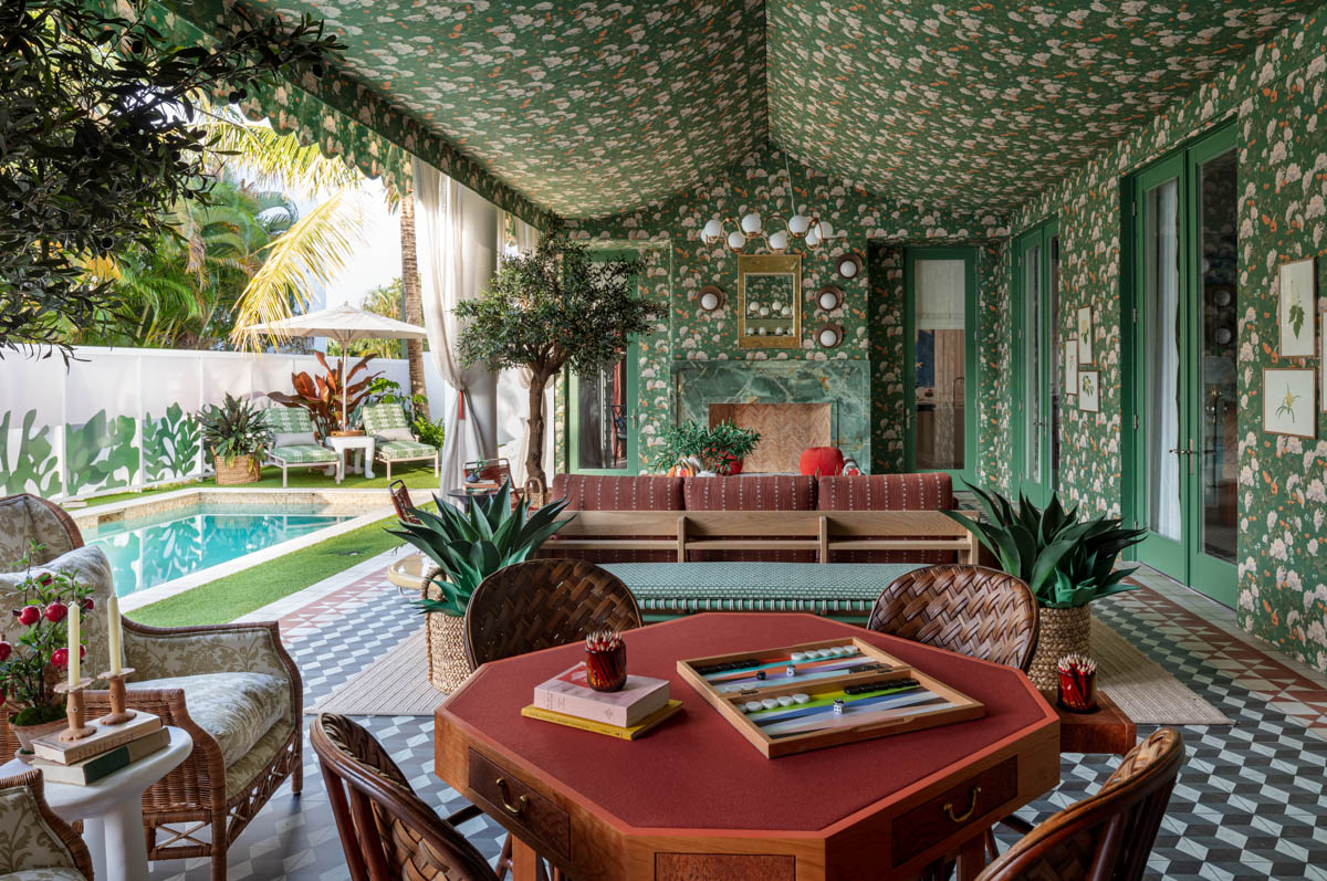 a green and white floral wallpapered poolside lounge with a game table and sofa