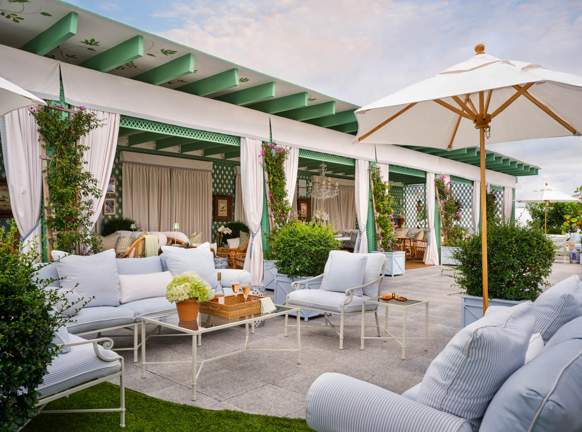 a green and white indoor-outdoor pavilion with powder blue furniture and other coastal elements