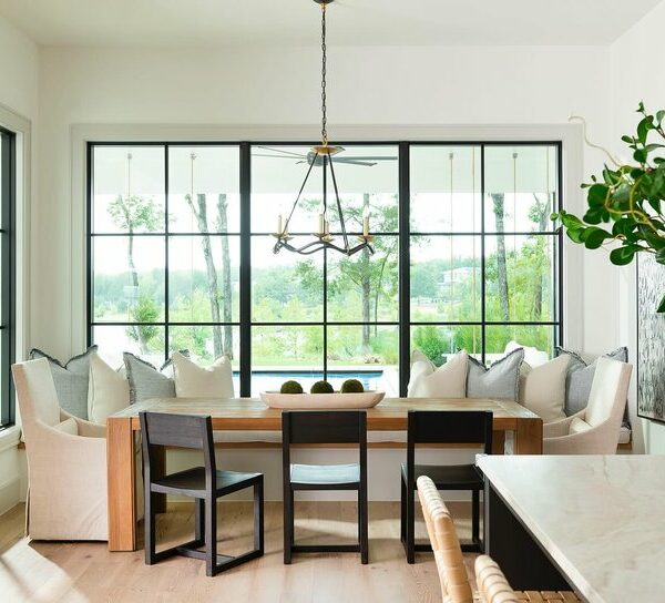 A cozy dining nook with a table and chairs, surrounded by big windows, creating a warm and inviting atmosphere.