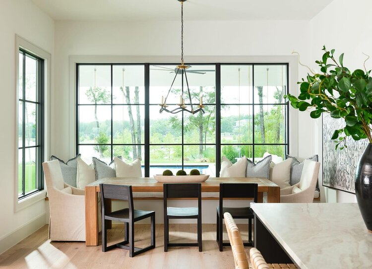 A cozy dining nook with a table and chairs, surrounded by big windows, creating a warm and inviting atmosphere.