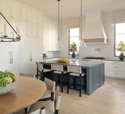 A kitchen with white cabinets and a dining table. Blue accent island seating adds a pop of color.