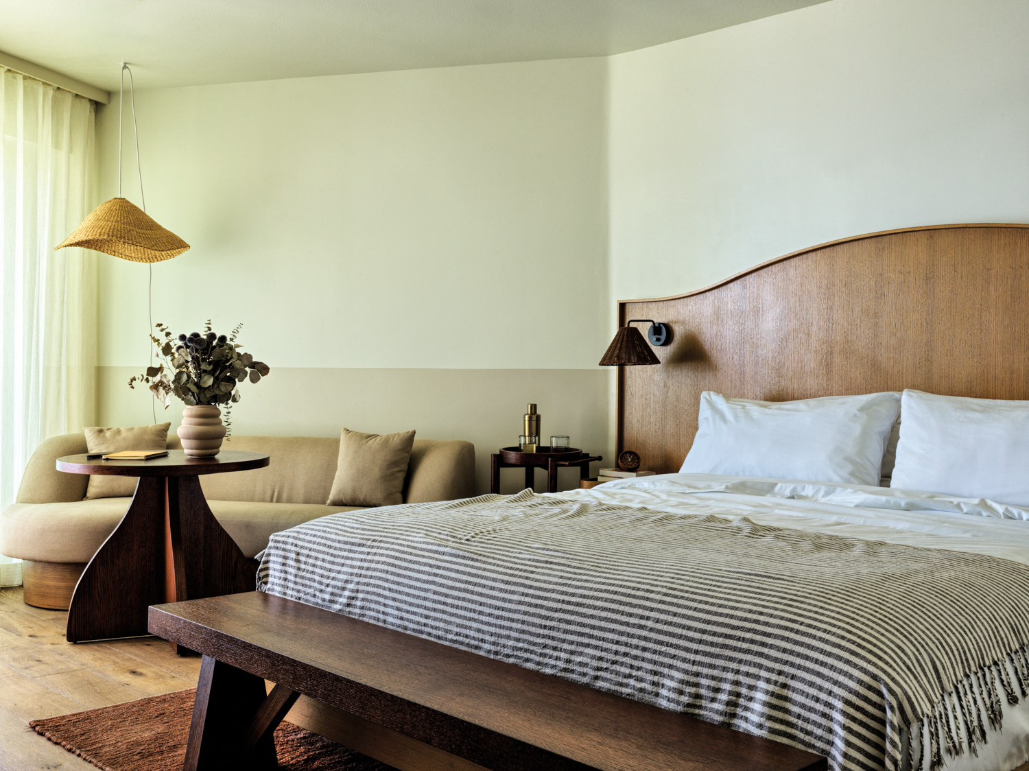 hotel bedroom featuring a wooden headboard and bench framing a bed with striped bedding