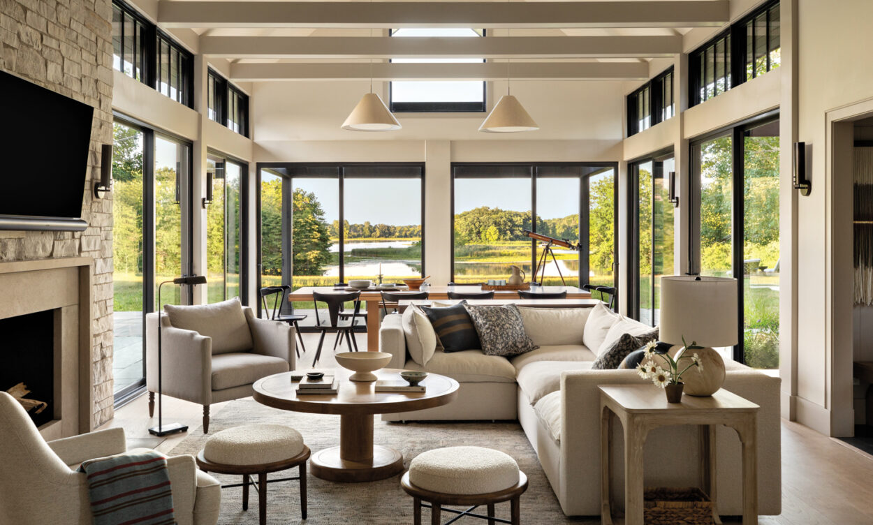 living room with white seating, a limestone fireplace and floor-to-ceiling windows