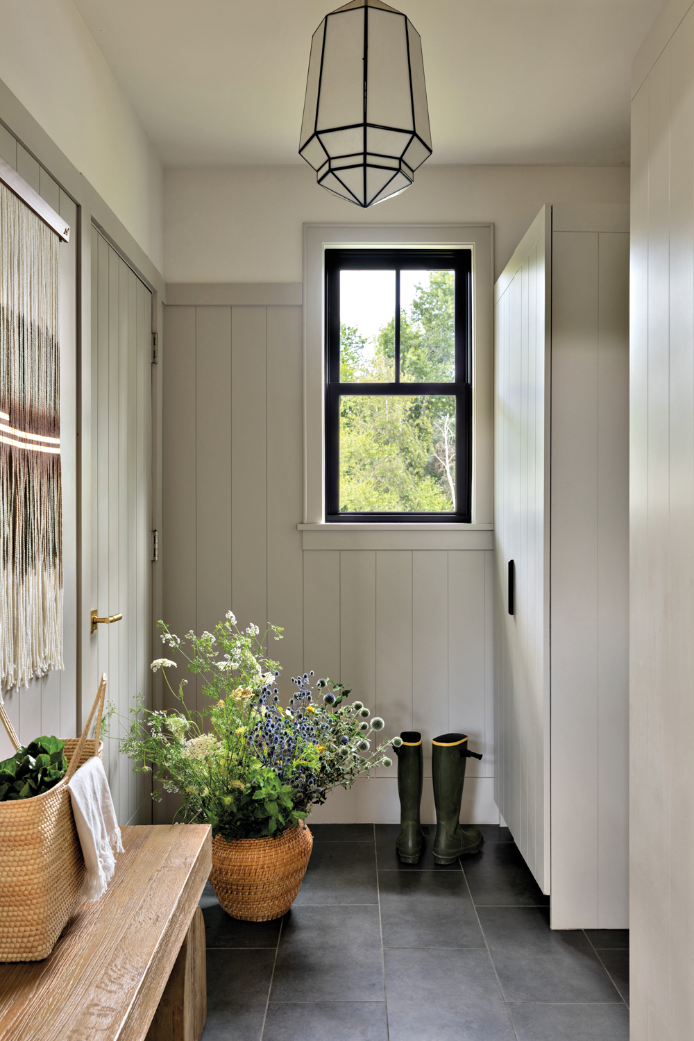 mudroom with white tongue-and-grooved paneling,...