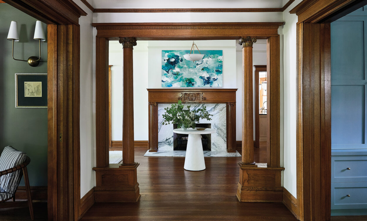 entry to a Victorian home with wood moldings and a marble fireplace with a wood mantle