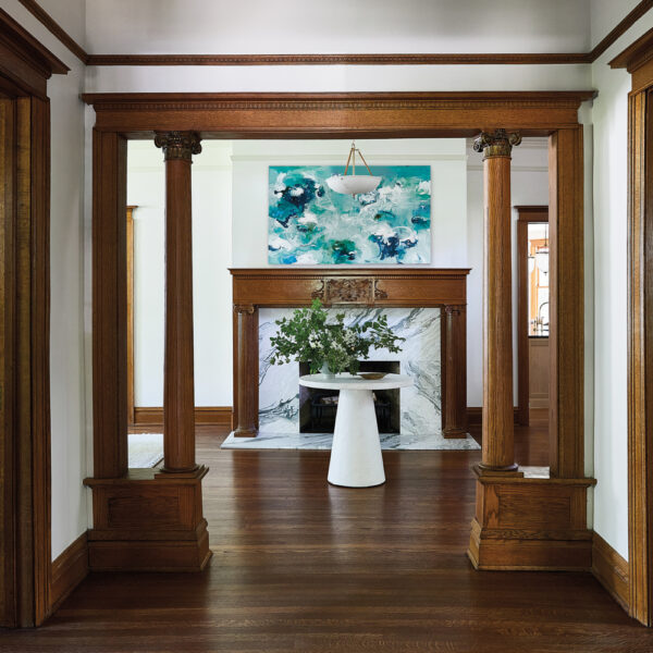 entry to a Victorian home with wood moldings and a marble fireplace with a wood mantle