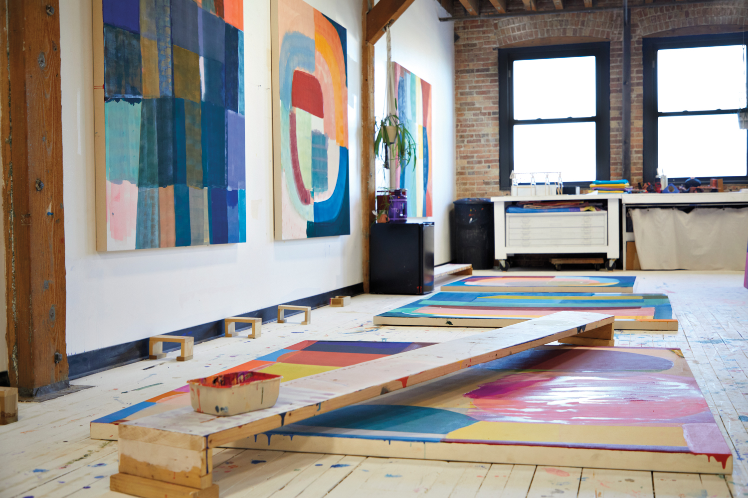 inside artist Anna Kunz's studio with abstract, colorful paintings on the floor and wall