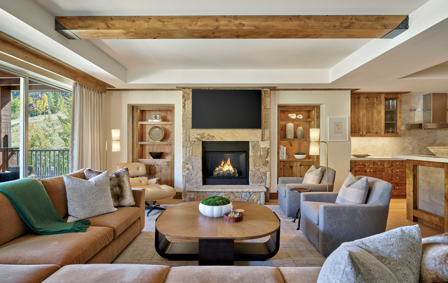A living room with a fireplace and an assortment of armchairs and sofas around a large, round wooden coffee table.