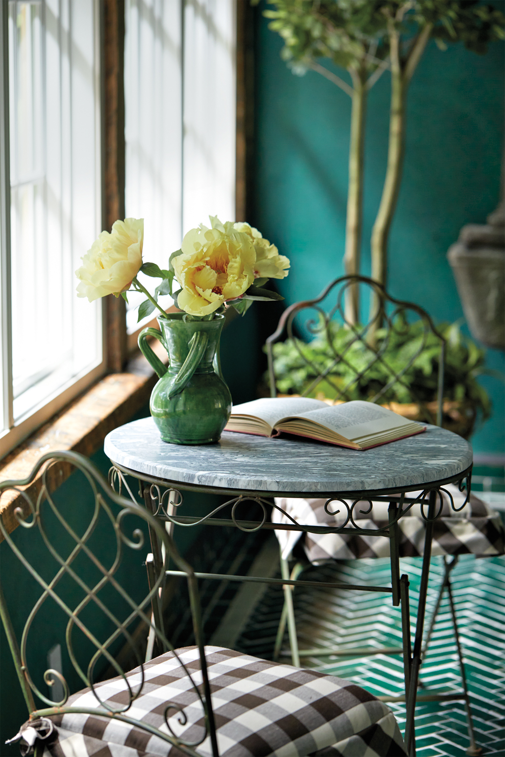 vignette of yellow flowers in a vase in a green garden room