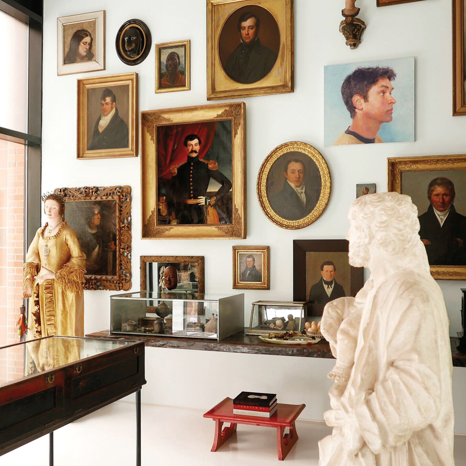 gallery wall of antique portraits with gold frames in an antique shop