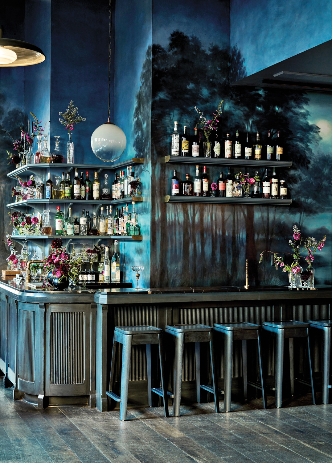 cocktail bar with a painted mural of a dark-blue forest landscape