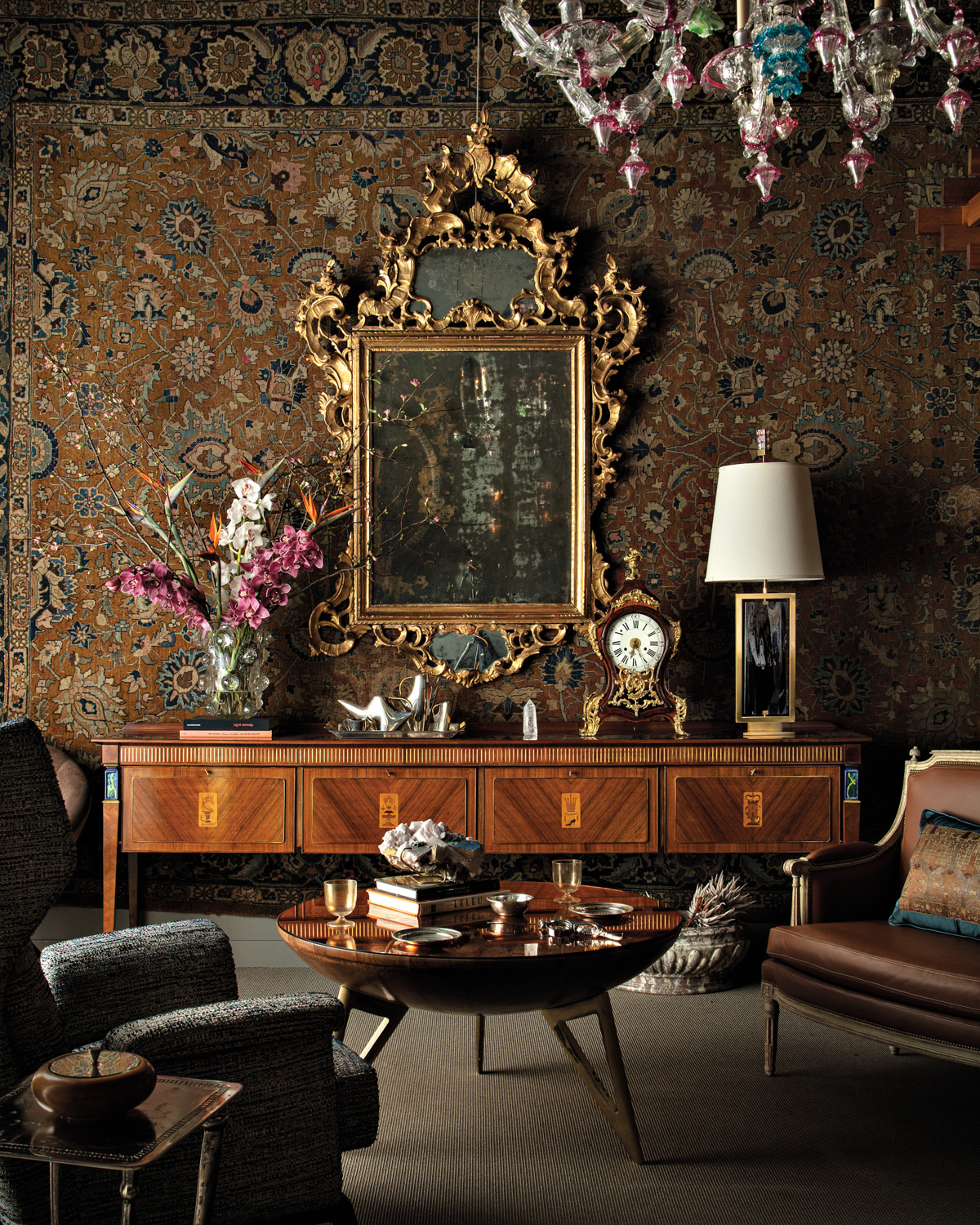 antiques shop with a gilt-frame mirror hanging against patterned wallpaper and a vintage console