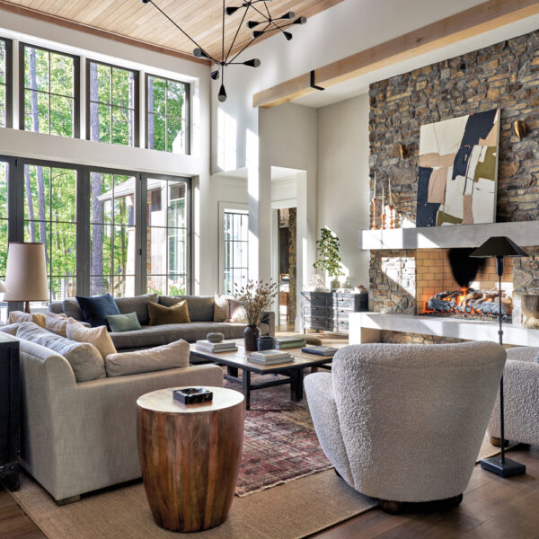 Sunlit living room with tumbled stone fireplace, modern chandelier and light-colored upholstery