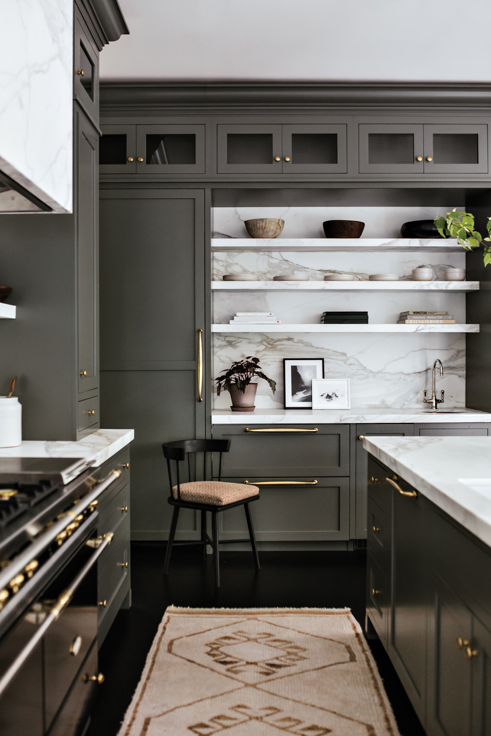 Kitchen with green-gray cabinetry, veined...