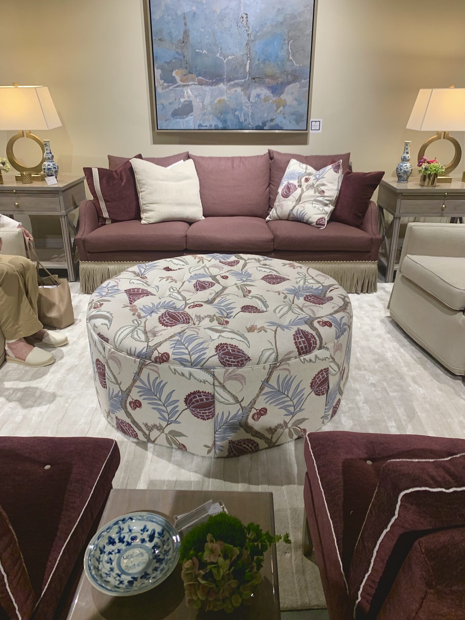 Living room seating group with large floral ottoman, plum-colored sofa and plum-colored armless chairs