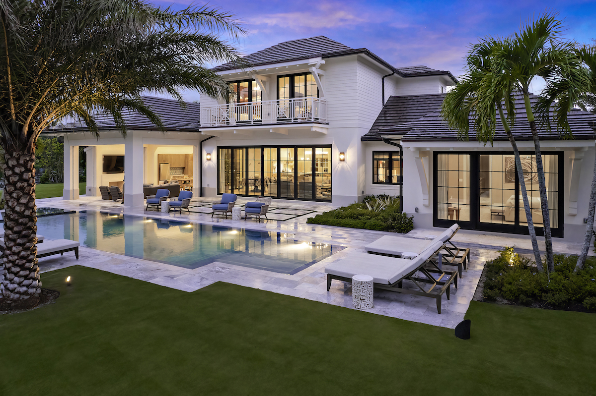 Elegant house featuring pool and palm trees.