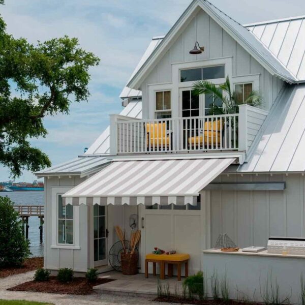 A charming white house with a balcony and awning, perfect for enjoying the outdoors.