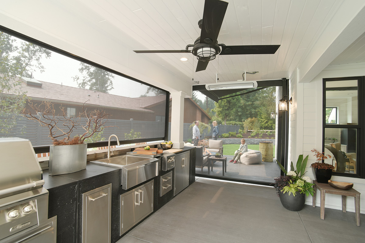 Modern outdoor kitchen with sink, fridge, and automatic shades.
