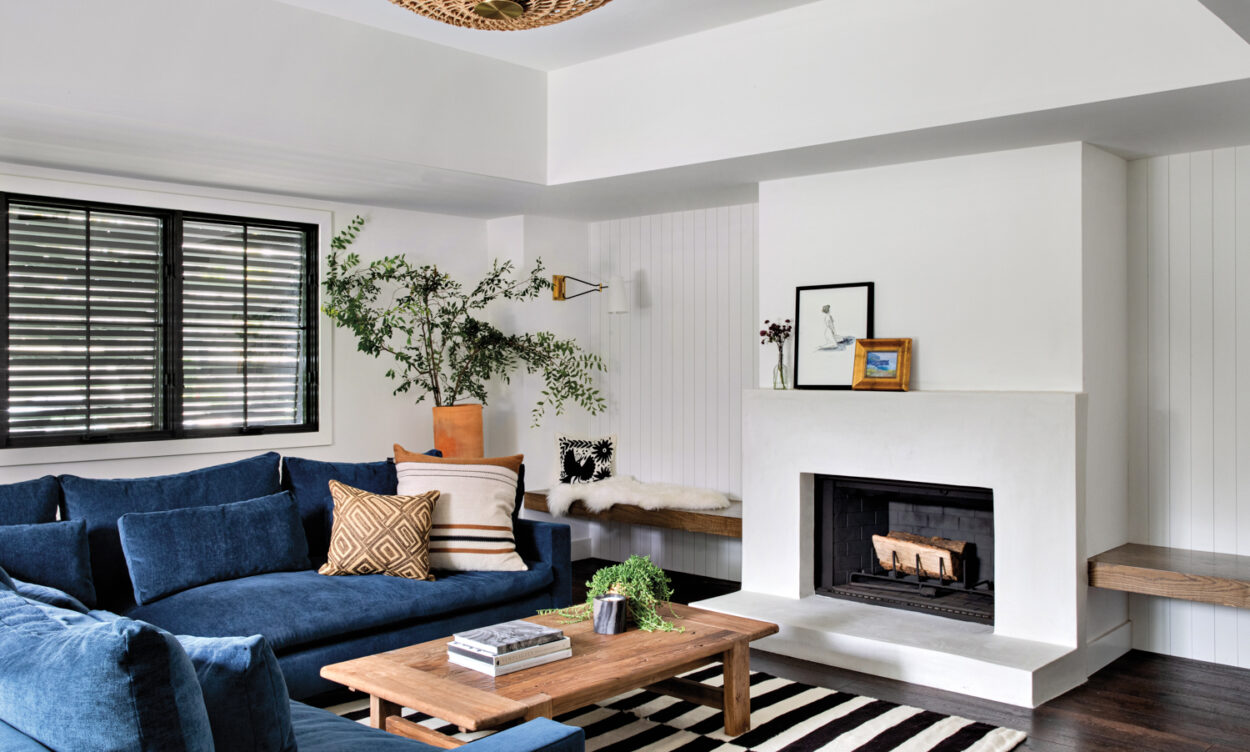 family room with blue sectional, black and white rug and fireplace, with a raffia pendant overhead