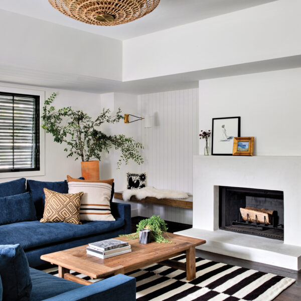 family room with blue sectional, black and white rug and fireplace, with a raffia pendant overhead